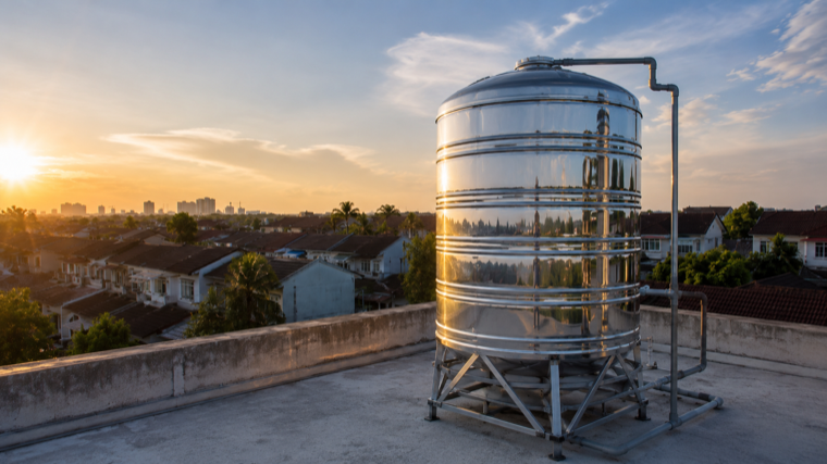 Tangki air stainless steel di bumbung ketika senja di kawasan perumahan